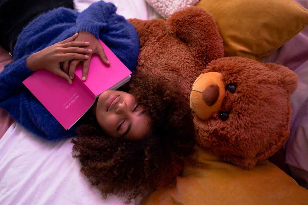 woman lying down on bed with her teddy bear
